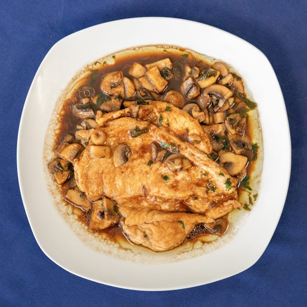 Milane's chicken and mushroom dish, featuring tender chicken in a rich brown sauce with sliced mushrooms.
